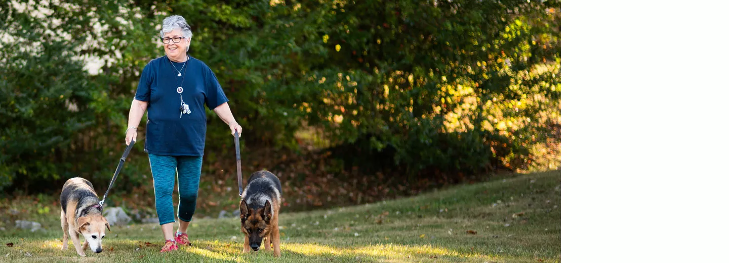 Smiling woman walking two dogs in a field