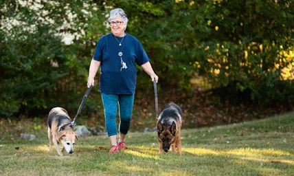 Smiling woman walking two dogs in a field