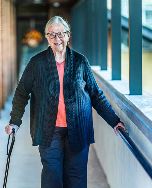 Older woman walking in a breezeway with a walking cane