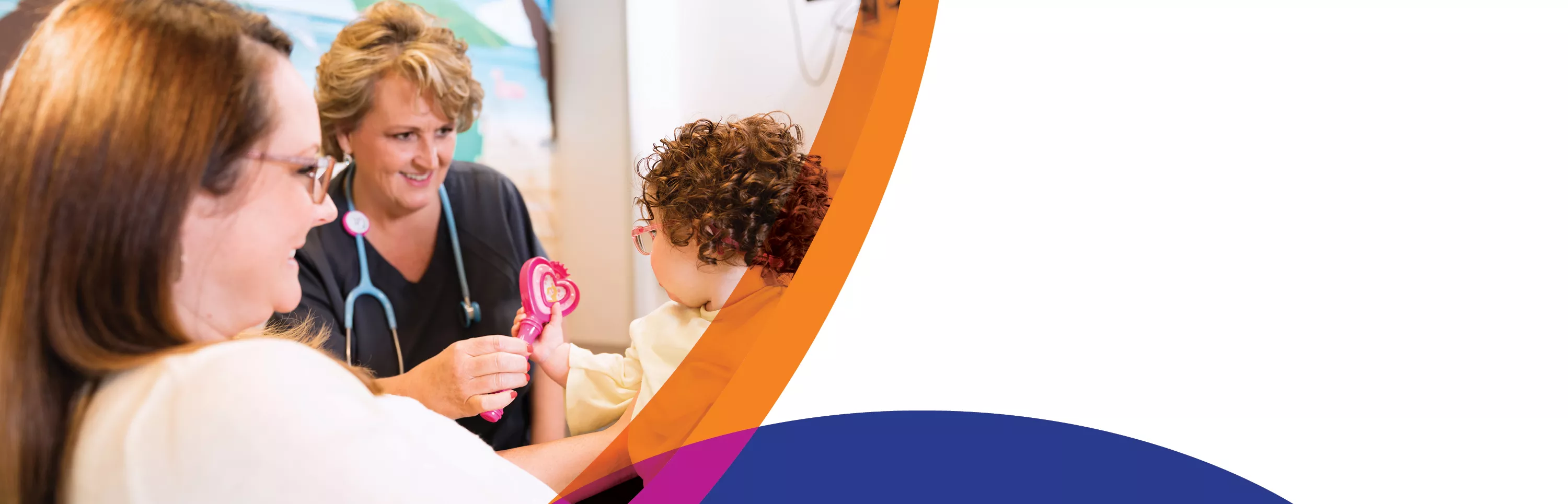 Young girl looking at heart-shaped rattle with nurse and mother